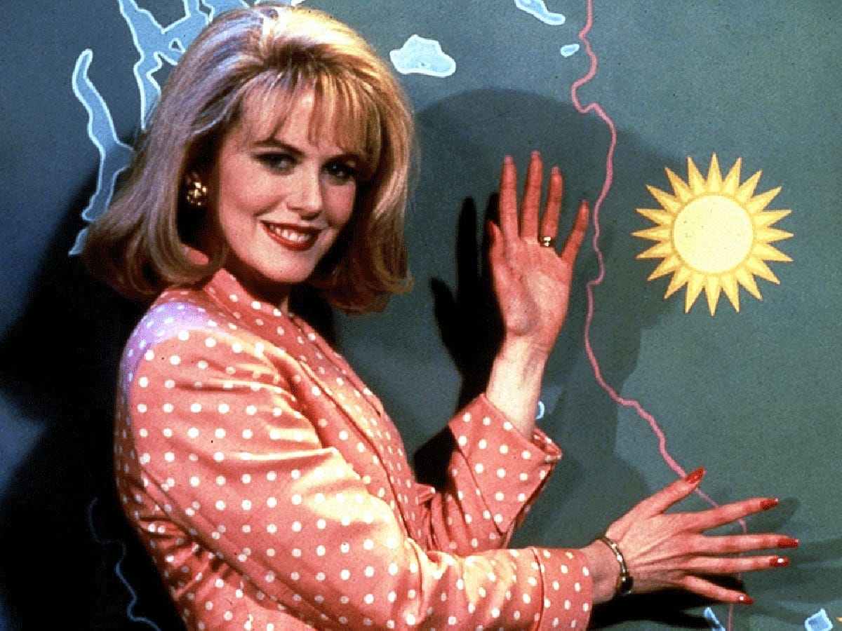 A shot of Nicole Kidman in the movie To Die For, smiling and gesturing at the weather map behind her