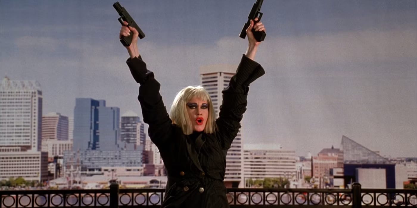 Melanie Griffith in a scene from Cecil B. Demented, with a crazy blonde wig, wild makeup, holding two guns in the air