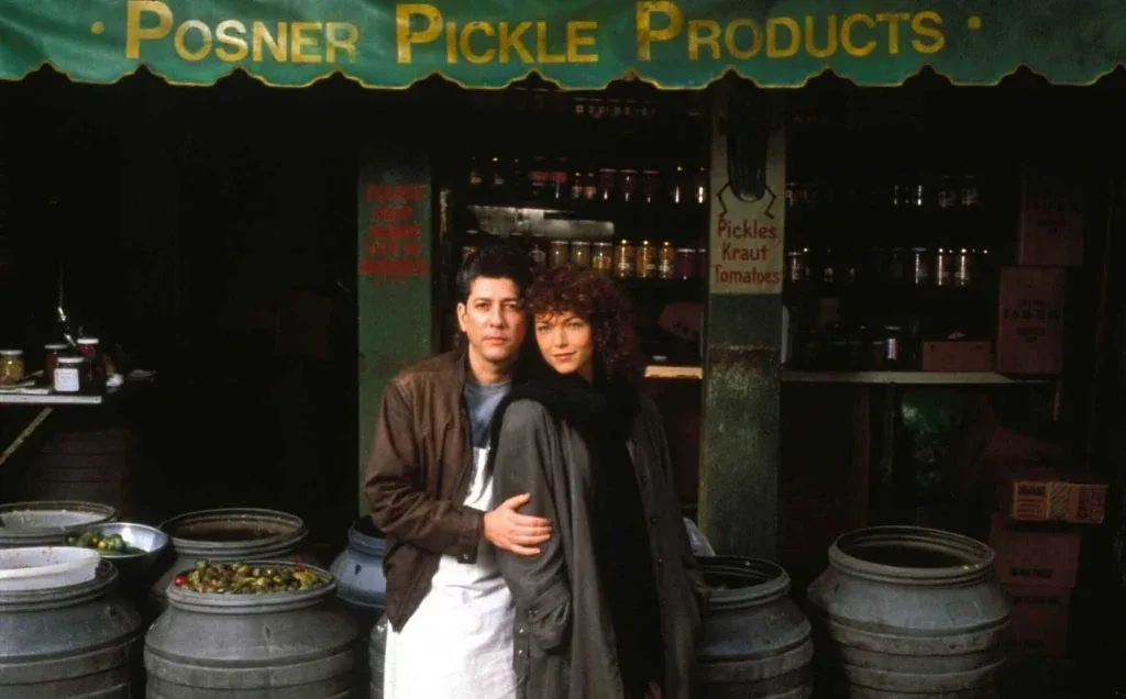 A shot of the two stars of Crossing Delancey, posing for the camera in each other's arms in front of the pickle store from the movie