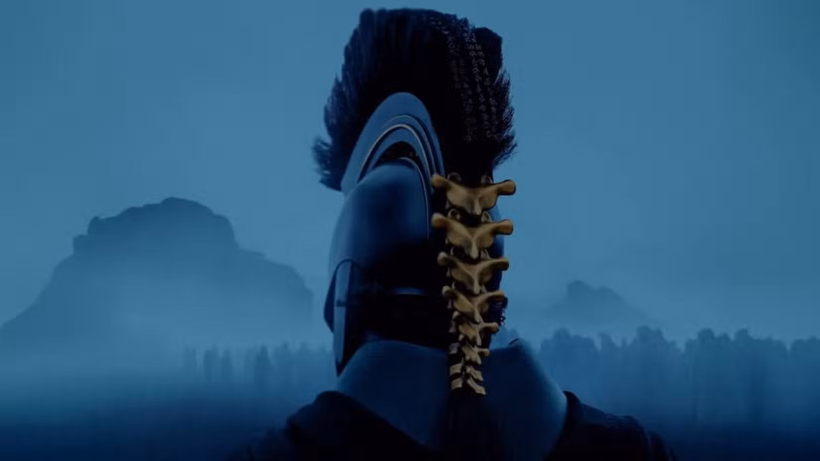 A man in an intimidating centurion's helmet with a gold spine running down the back looks out on a misty landscape with the figures of soldiers partially obscured 
