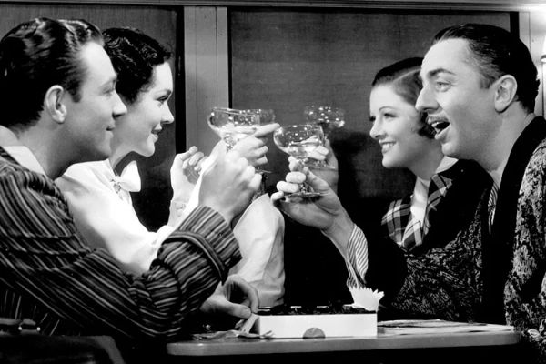 Four people clink champagne glasses on a train