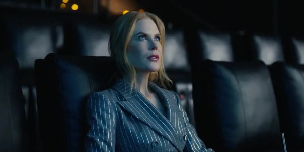 Nicole Kidman sits in an empty cinema in a pinstripe suit gazing at the screen in rapt attention