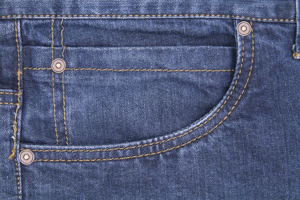 Detailed view of a denim jeans pocket with stitching and rivets, showcasing texture and tailoring.