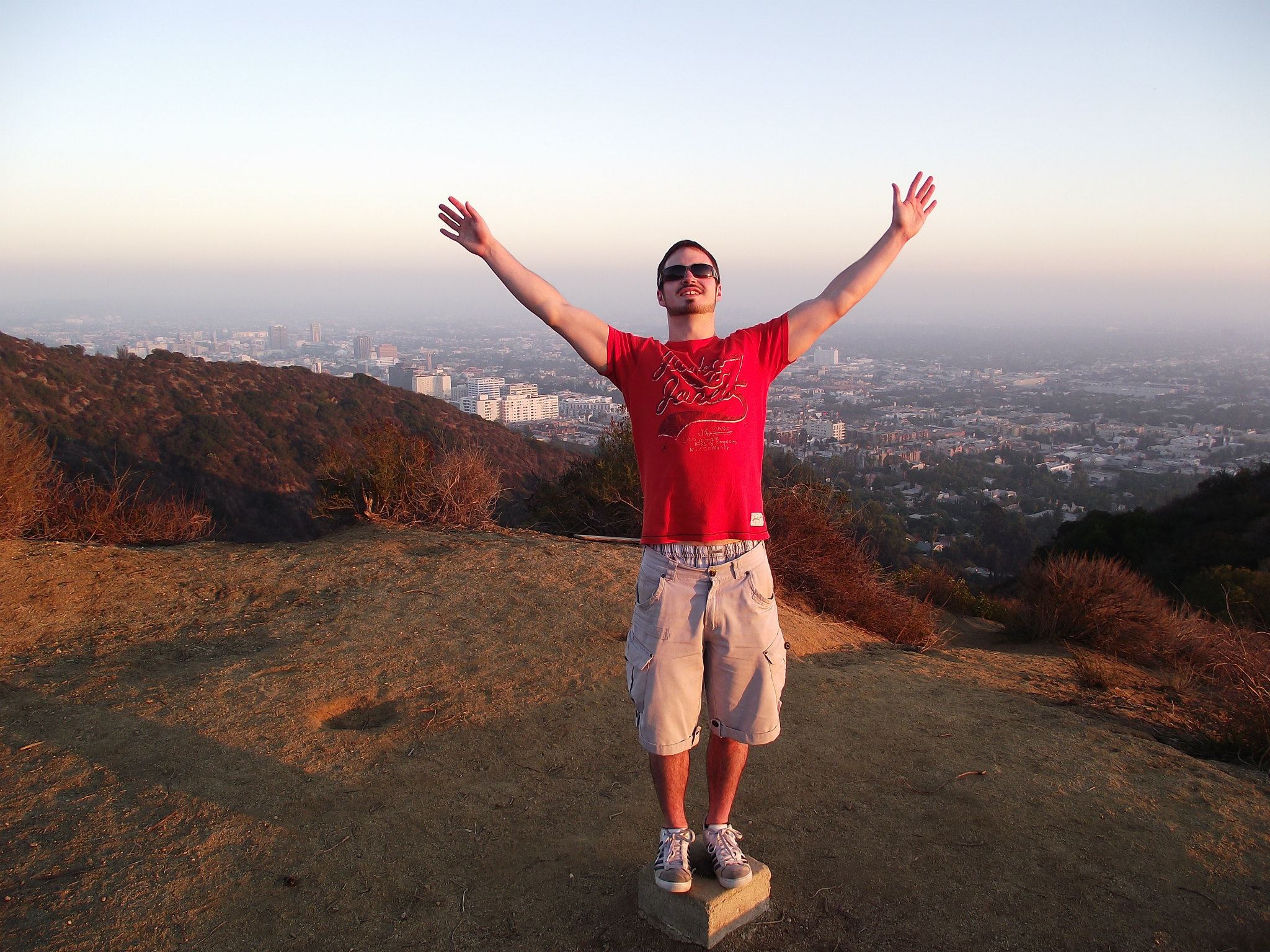 Man with beard in orange t shirt standing in the hills on the edge of LA
