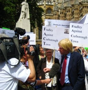 Michael Fabricant talking to the media with protestors
