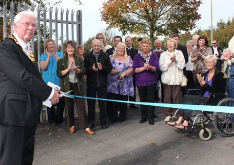 Cllr Bernard Derrick cuts the ribbon on the Redwood Park gates