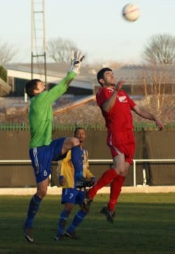 Liam Holt tries to rise highest under pressure from the Sporting Khalsa keeper. Pic: Mick Tyler