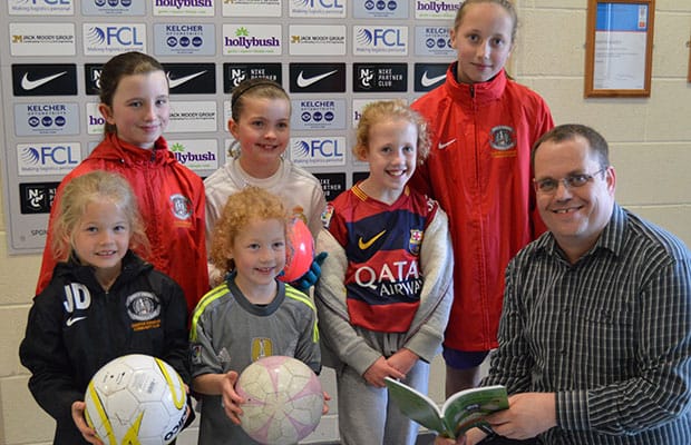 Paul Mullins handing over signed copies of his book to young footballers
