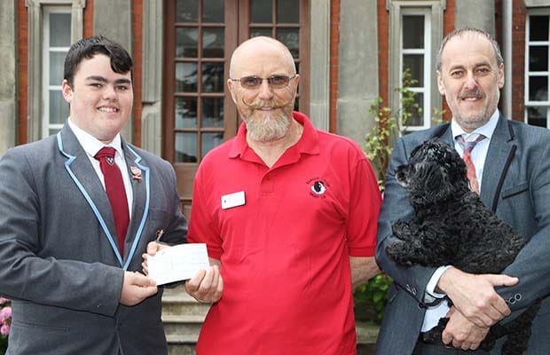 Ben Owen hands over the cheque to Border Collie Trust’s Ben Wilkes with headteacher Dr Daryl Brown and school dog Lucy