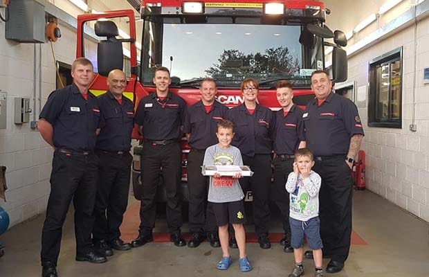 Firefighters receiving their doughnuts from a local Beaver Scout