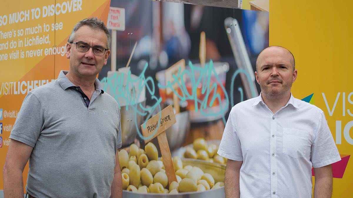 Cllr Paul Ray and Cllr Miles Trent in front of one of the hoardings