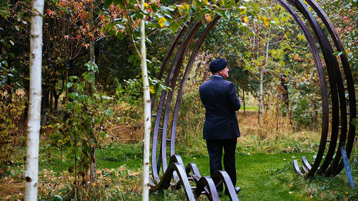 Terry Barnett beneath a curved oak sculpture leading to the centre of the Remembrance Glade