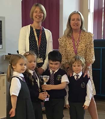 Liz Leyshon hands over the reading challenge trophy to pupils and headteacher Dee McLeary