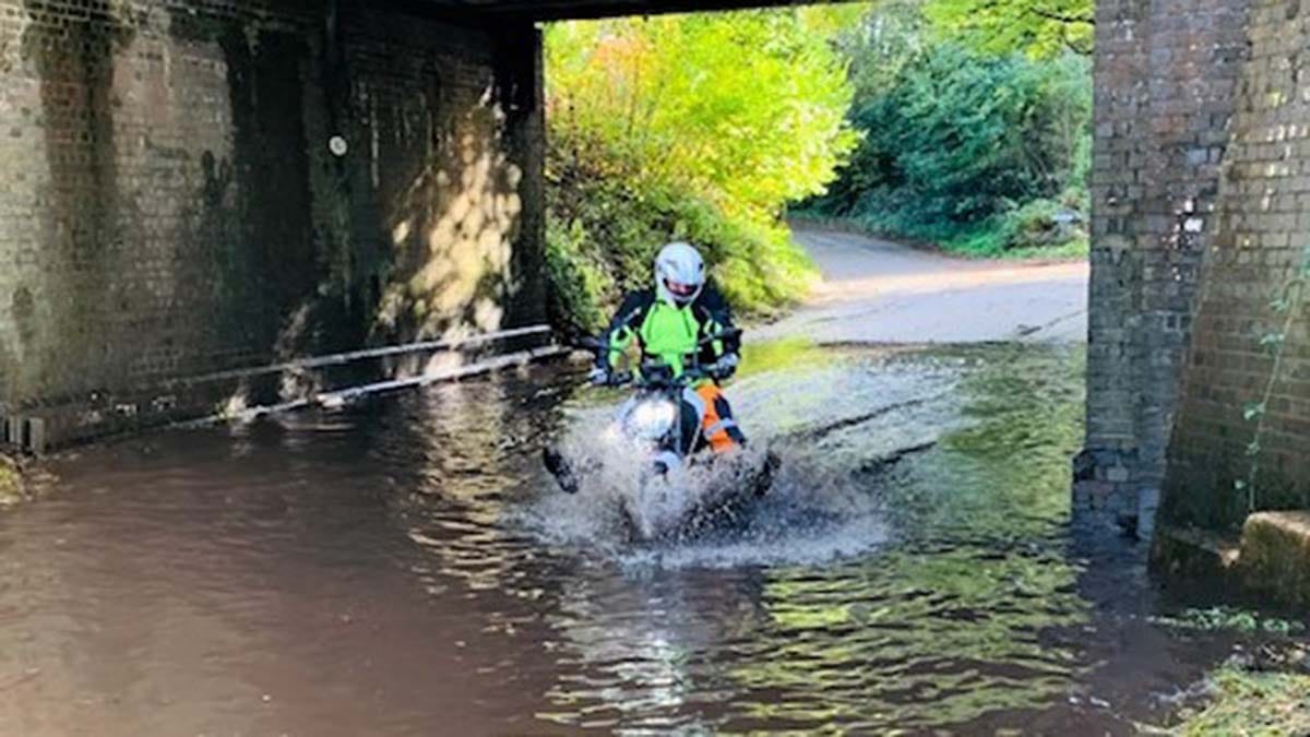 A biker tries to get through a flooded section of road in Hammerwich