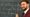 Sam O'Neill stood in front of a blackboard with a piece of chalk
