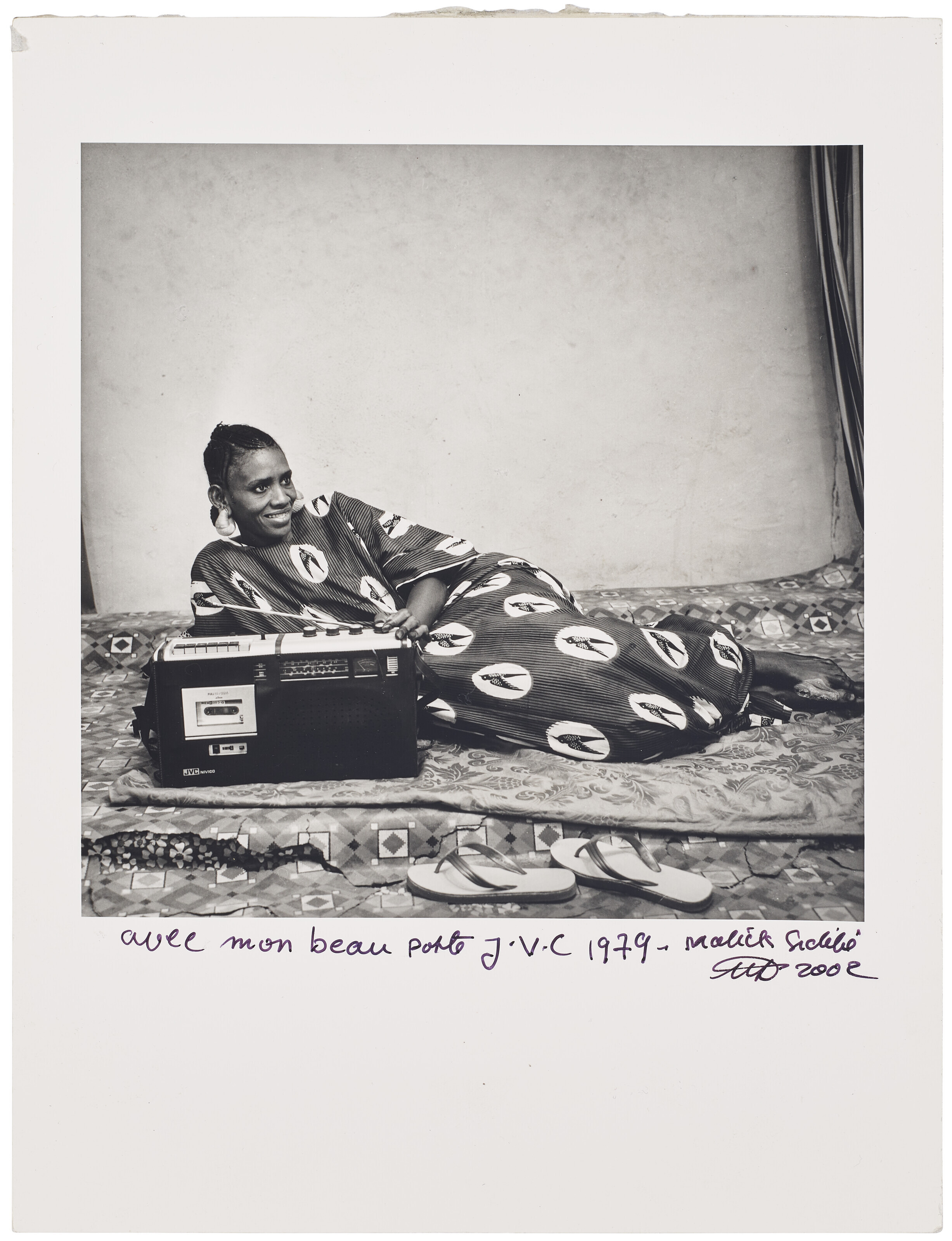 Black and white photograph by Malick Sidibé of a woman wearing wax print fabric featuring the Sika Wo Ntaban motif, Mali, 1960s