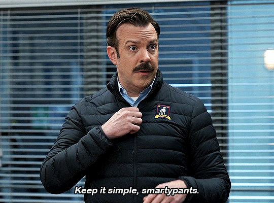 A .gif of Ted Lasso from the show of the same name, unzipping a black winter jacket and saying, "keep it simple, smartypants."