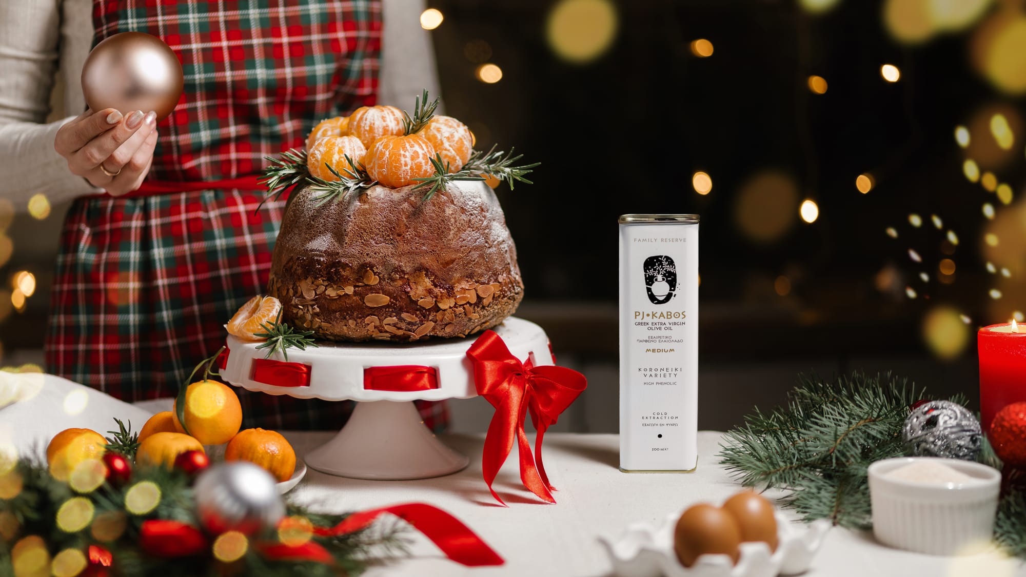 An olive oil/yeast cake with tangerines decorating it and a tin of Extra Virgin Olive Oil used in making it sitting on a holiday-time table
