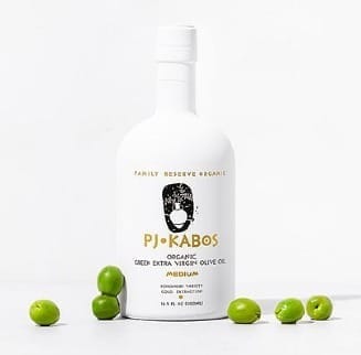 An elegant white bottle of PJ Kabos Medium High Phenolic Extra Virgin Olive Oil with olives scattered around it. Finishing oil, cooking oil and a phenolic shot.