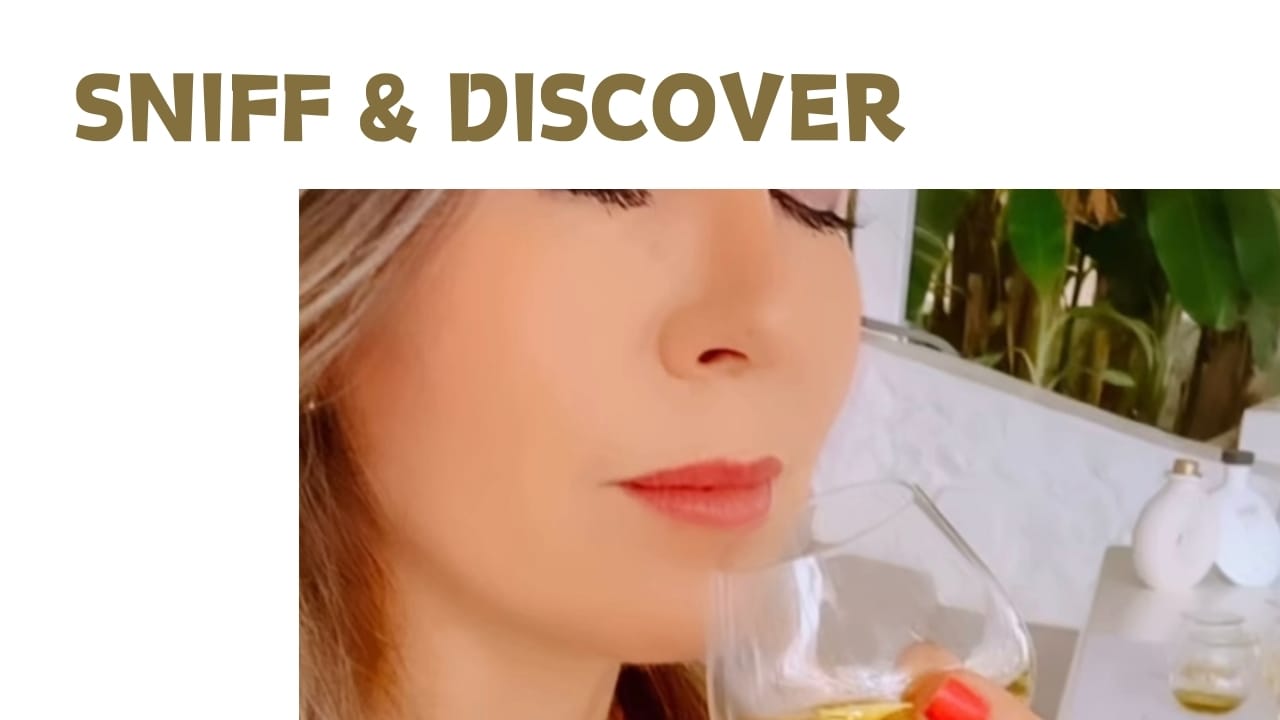 Attractive woman with eyes closed sniffing glass of olive oil.