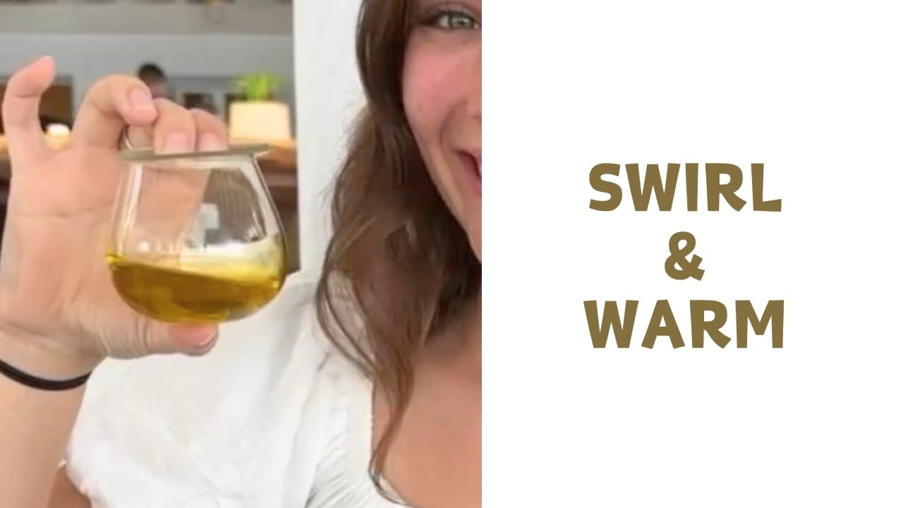 Close-up of swirling olive oil glass to warm it at an elegant tasting.