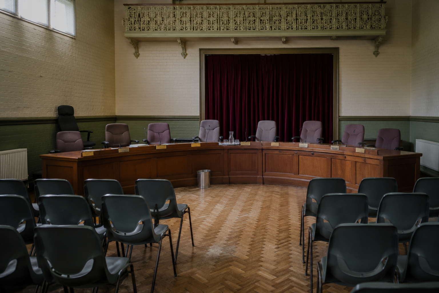An empty council chamber with a curved desk and vacant seats