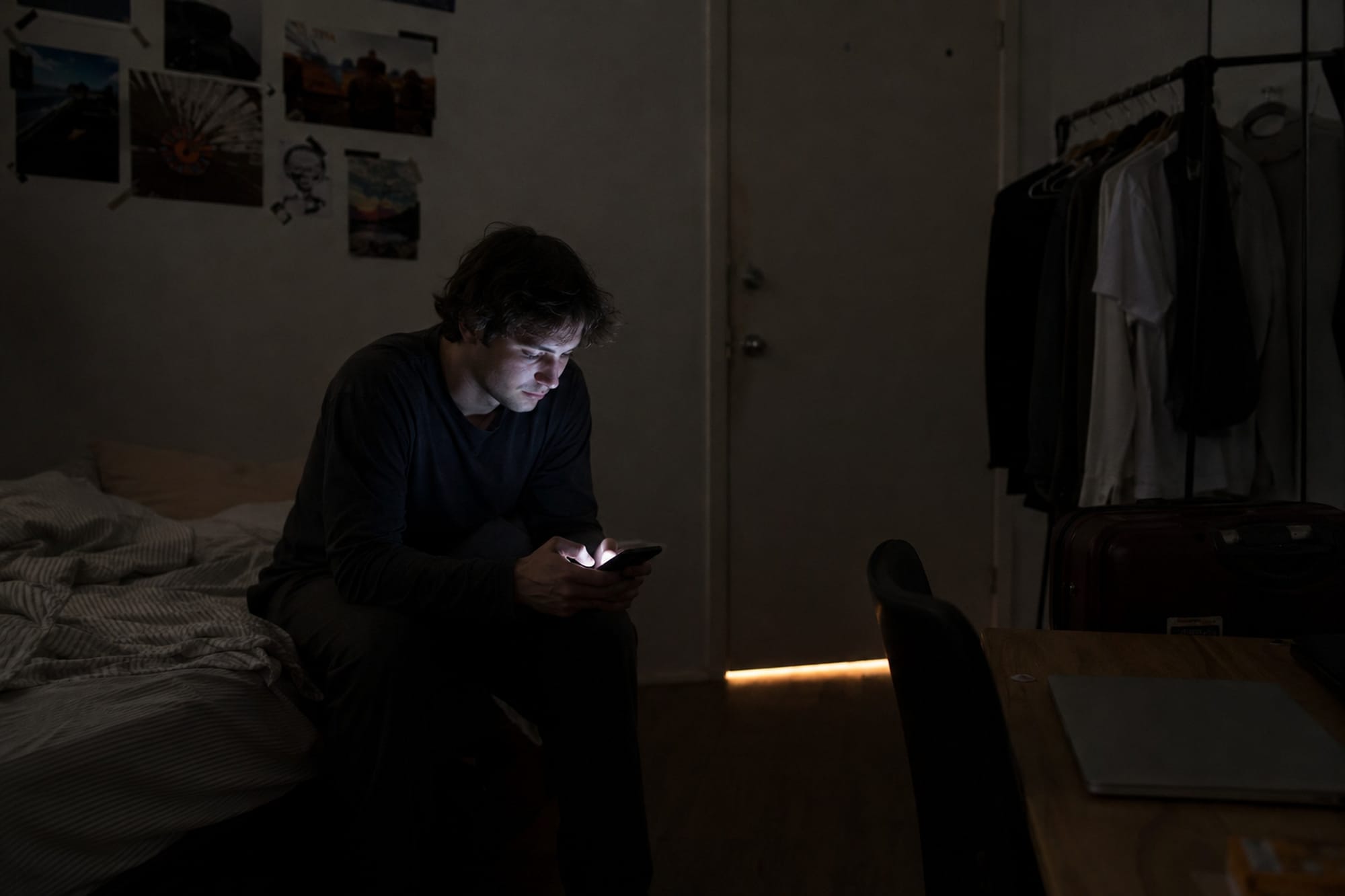 A person alone in a dark bedroom at night filling in a form on a phone