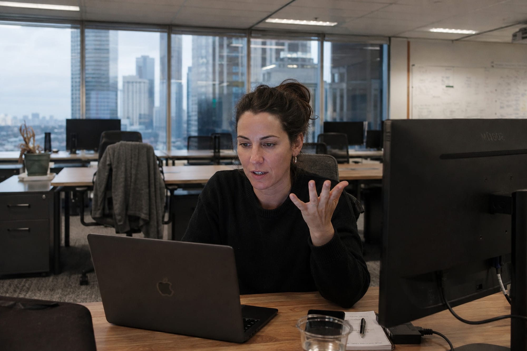 A woman on a video call at a desk in a Melbourne office with most of the surrounding desks empty