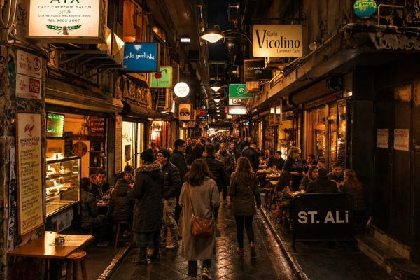 A packed Melbourne laneway at night with diners at outdoor tables under warm lights