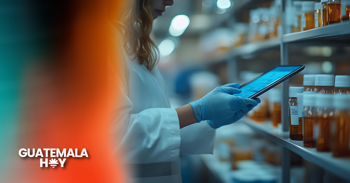 Profesional farmacéutica revisa tablet en laboratorio con frascos de medicamentos, como parte del proceso de farmacovigilancia en Guatemala.
