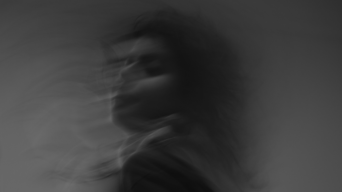 Ghostly and blurry picture of a face against a grey background