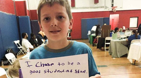 A US school kid holding a placard that reads "I chose to be a good student at school."