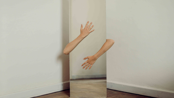 Two hands stretching out from behind a mirror and hugging it