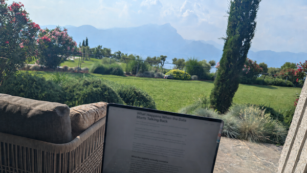 Laptop displaying a Heart Rhythm International article about cardiac device data, set on a terrace overlooking gardens and mountains in Italy.