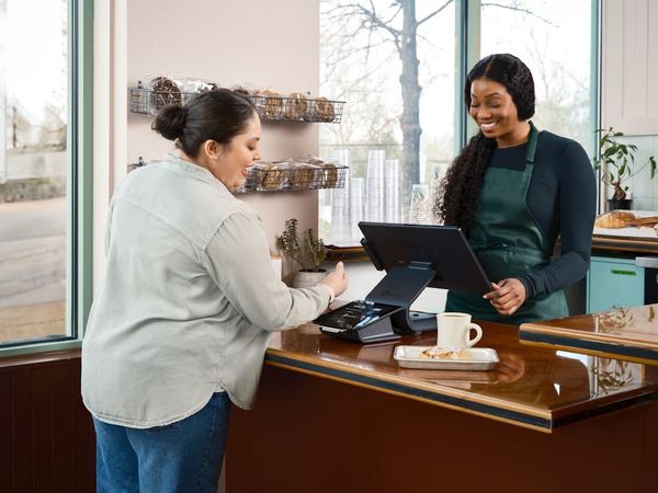 Customer pays cashier at a counter in a shop.
