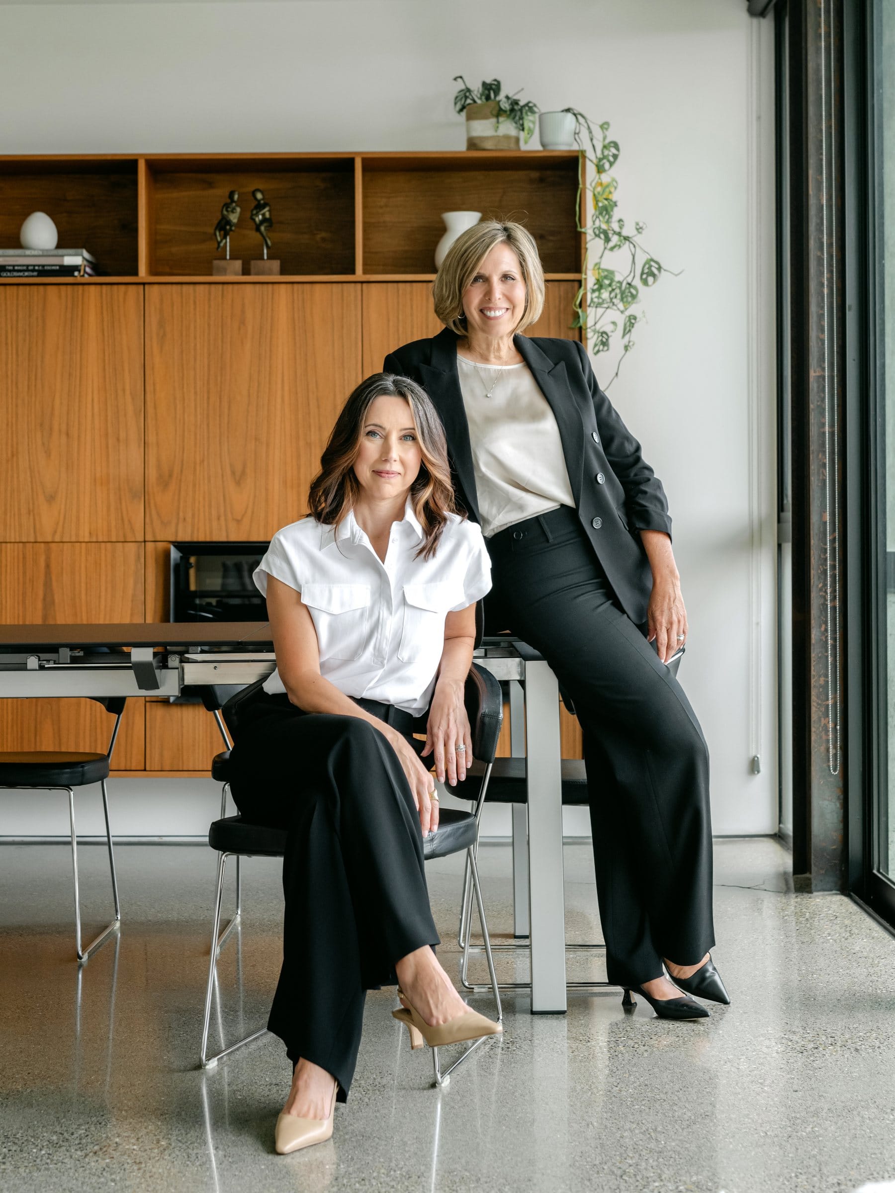 Two business partners in black-and-white outfits at a modern office table