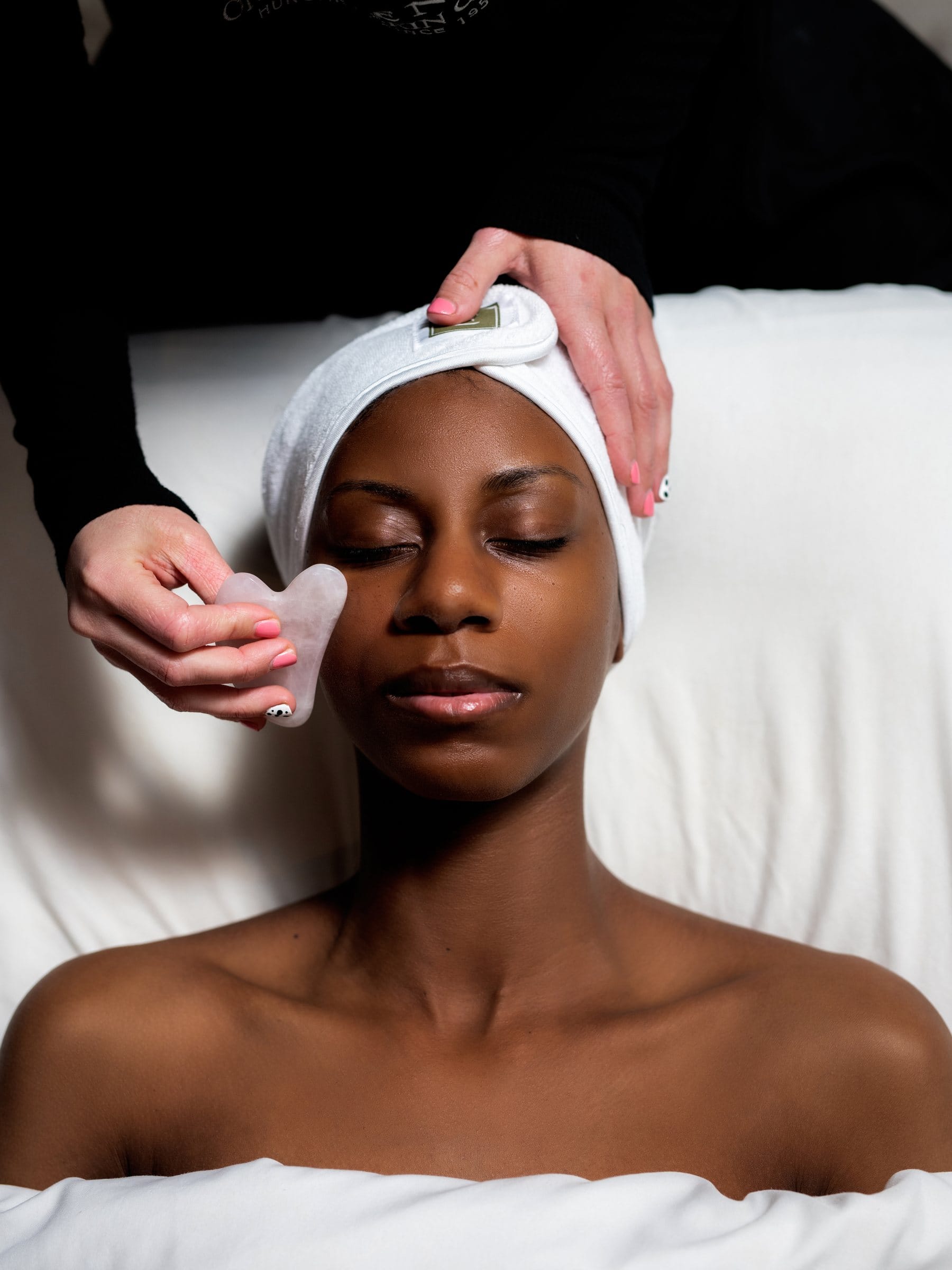 Esthetician giving a client a facial with a gua sha stone