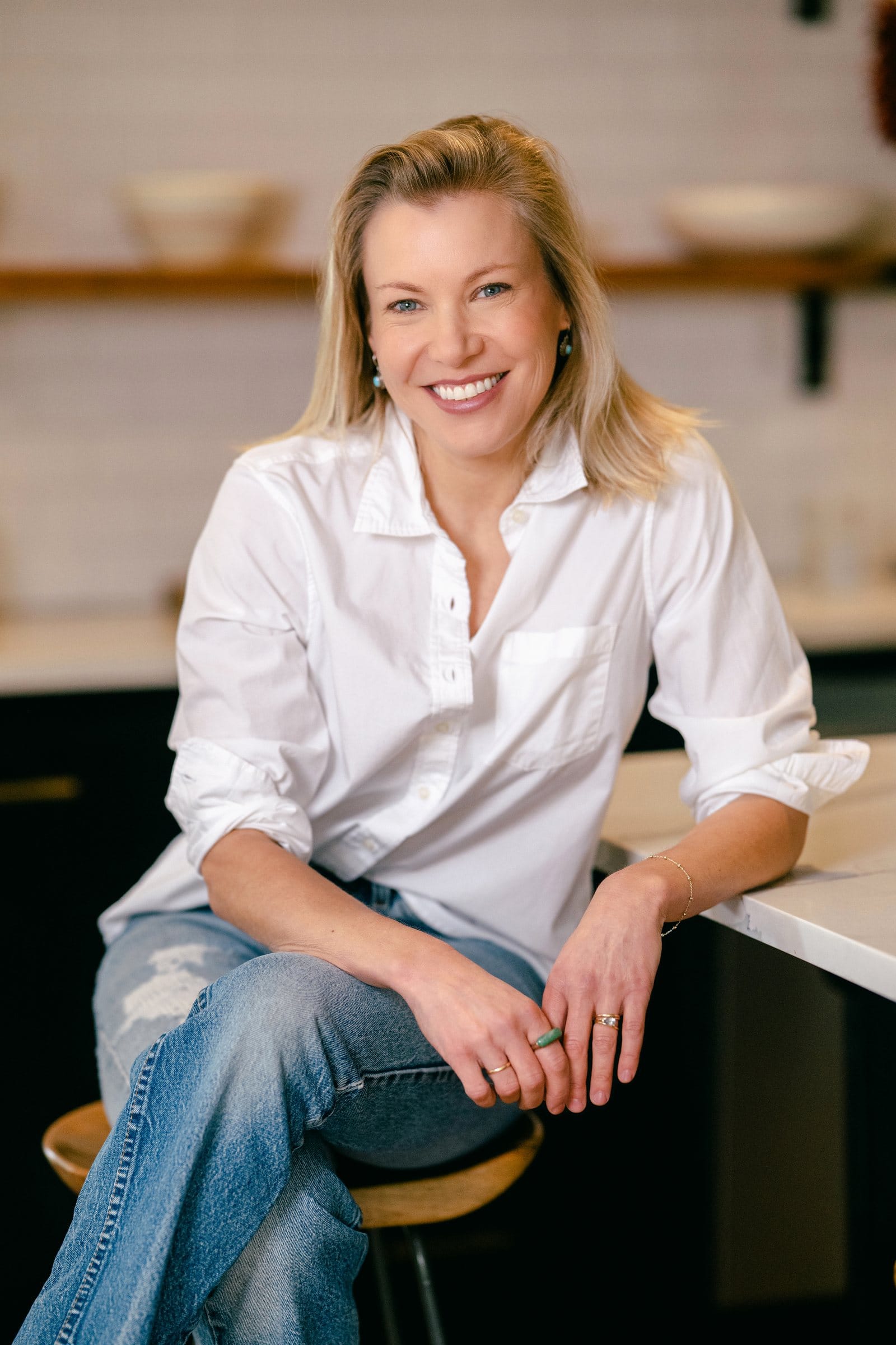 Founder in a crisp white shirt laughing at her kitchen counter