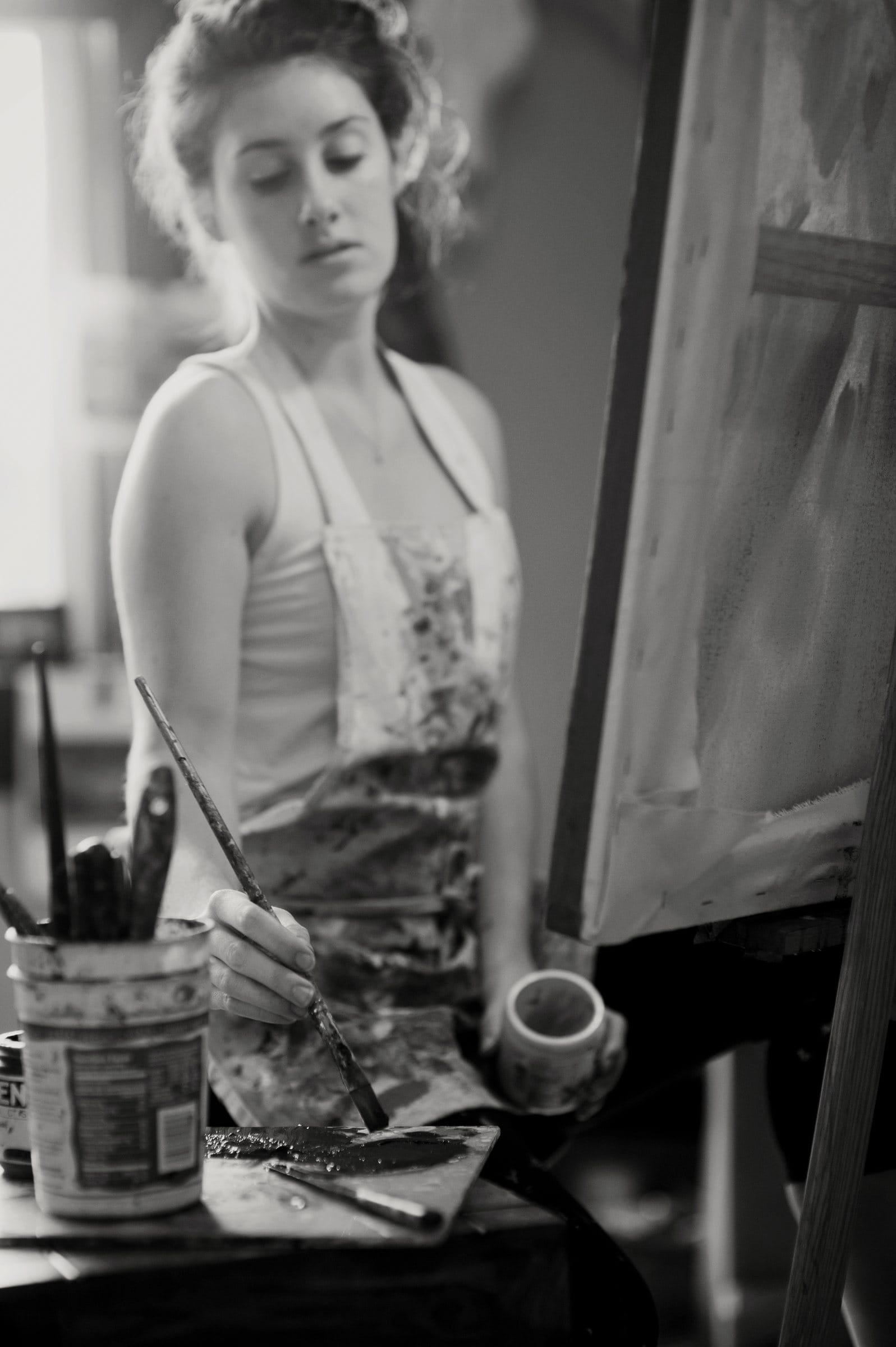 Black and white portrait of a painter at work at her easel