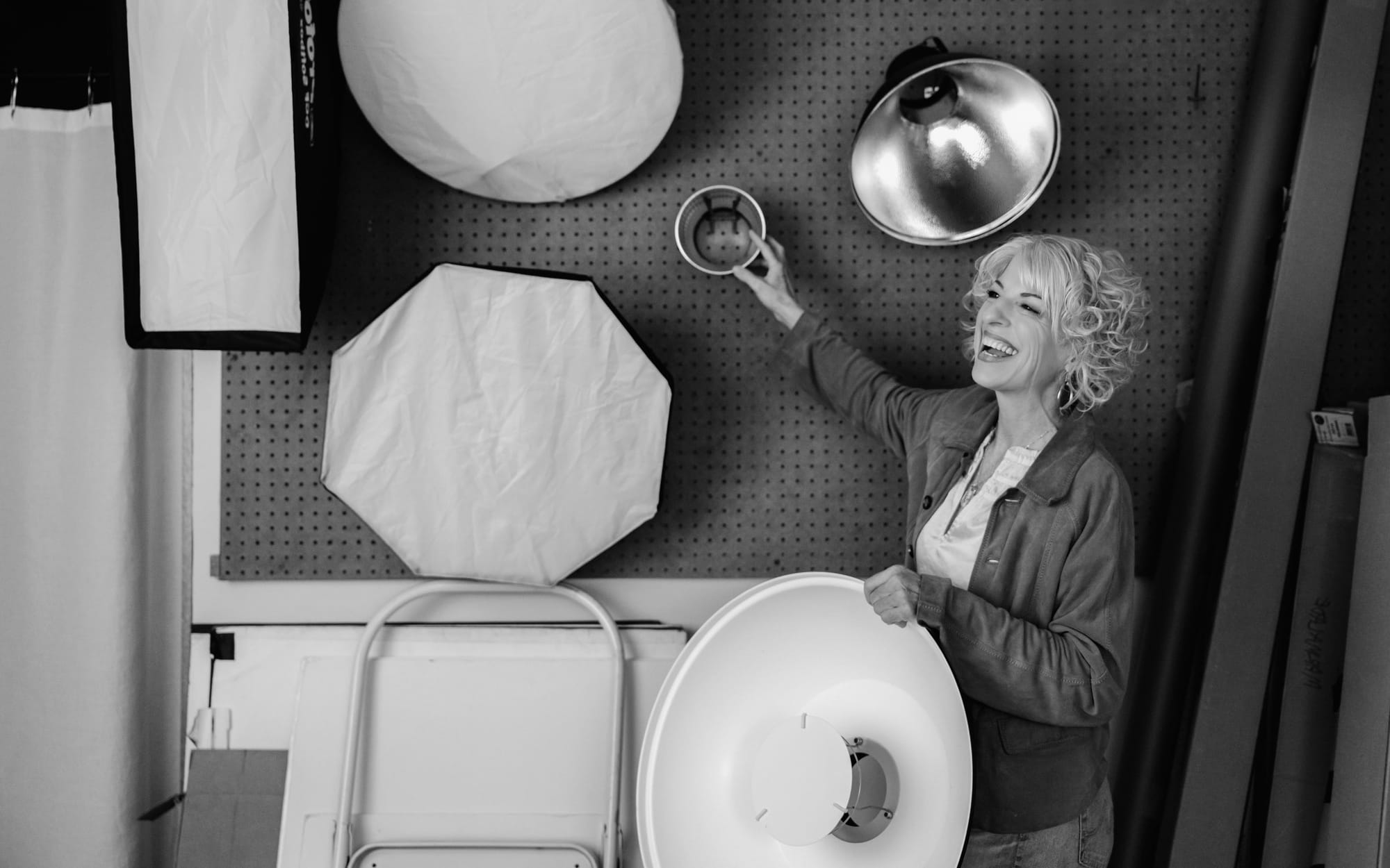 Black and white photo of a photographer reaching for lights in her studio