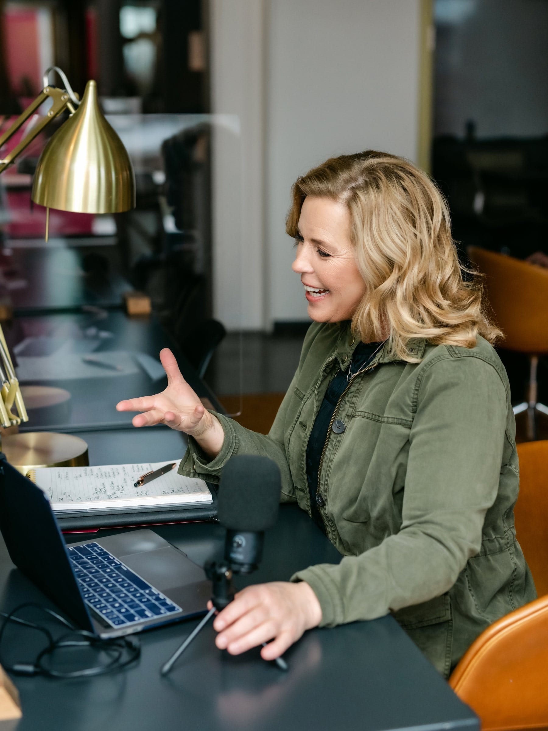 Podcaster talking into her microphone at her desk