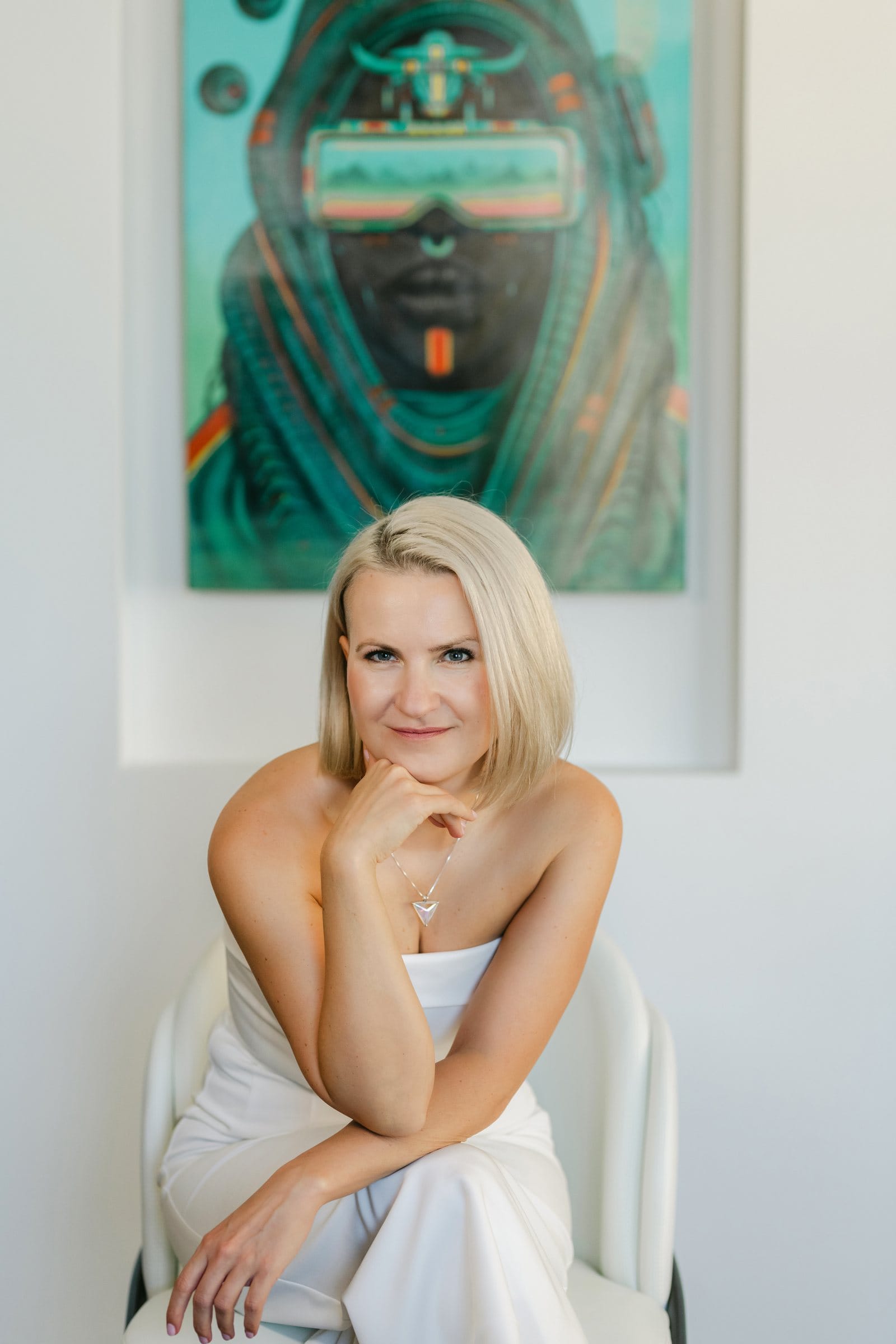 Woman in white seated beneath a vivid contemporary painting