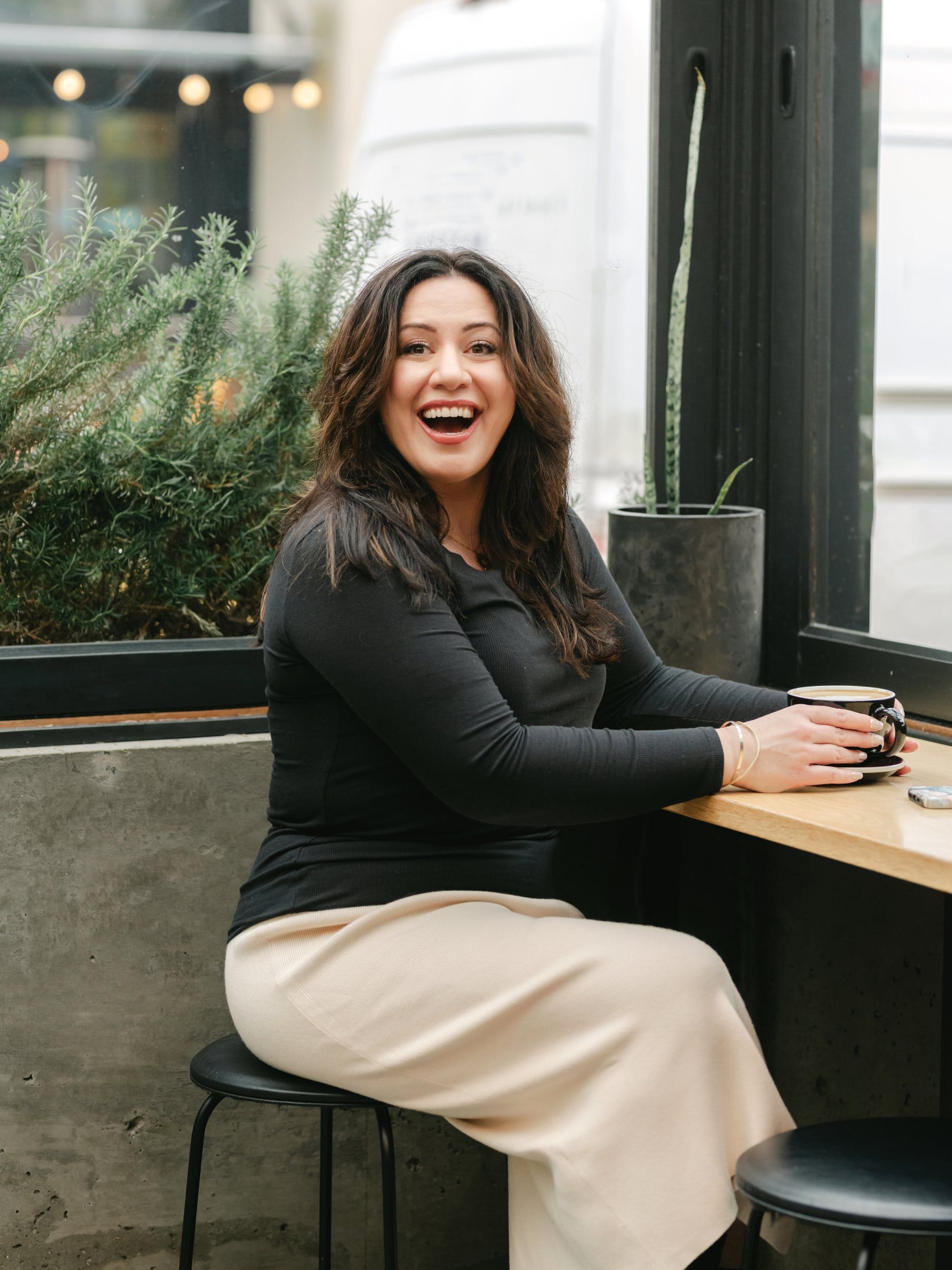 Woman laughing at a café window counter