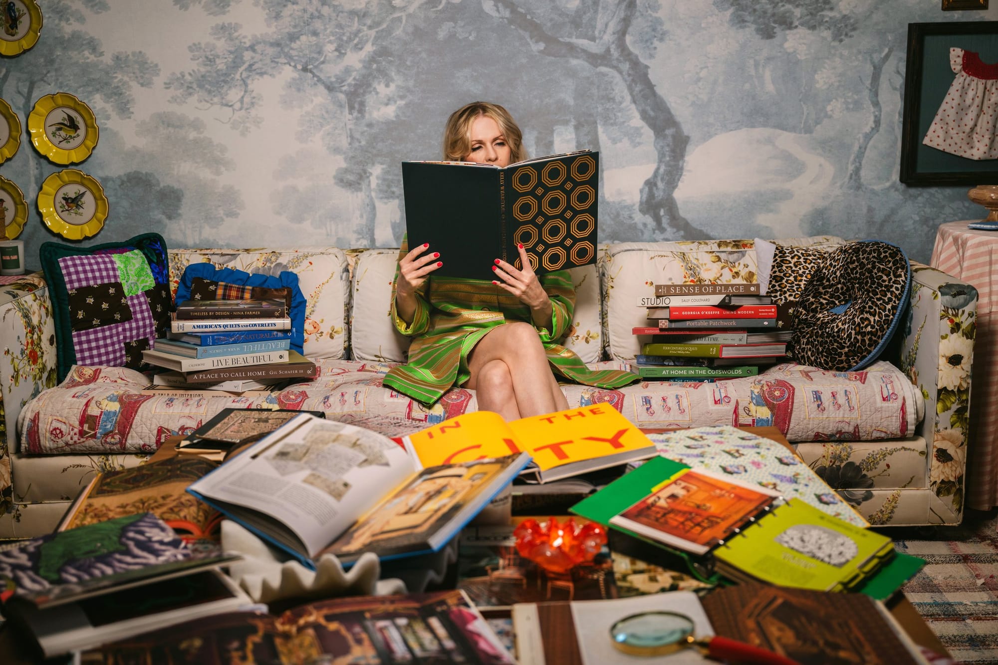 Woman reading on a vintage sofa surrounded by colorful art books