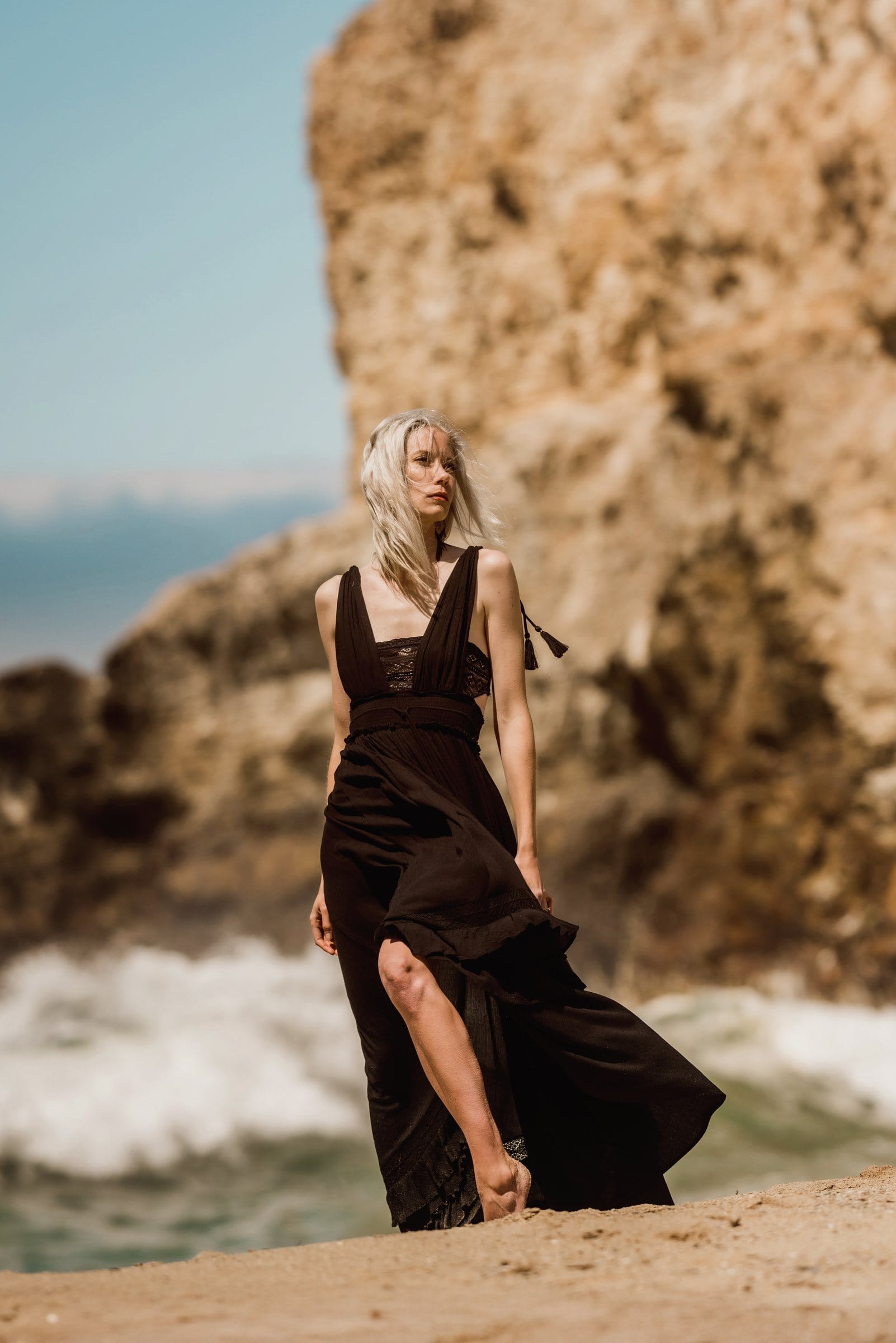 Woman in a flowing black dress on a rocky beach