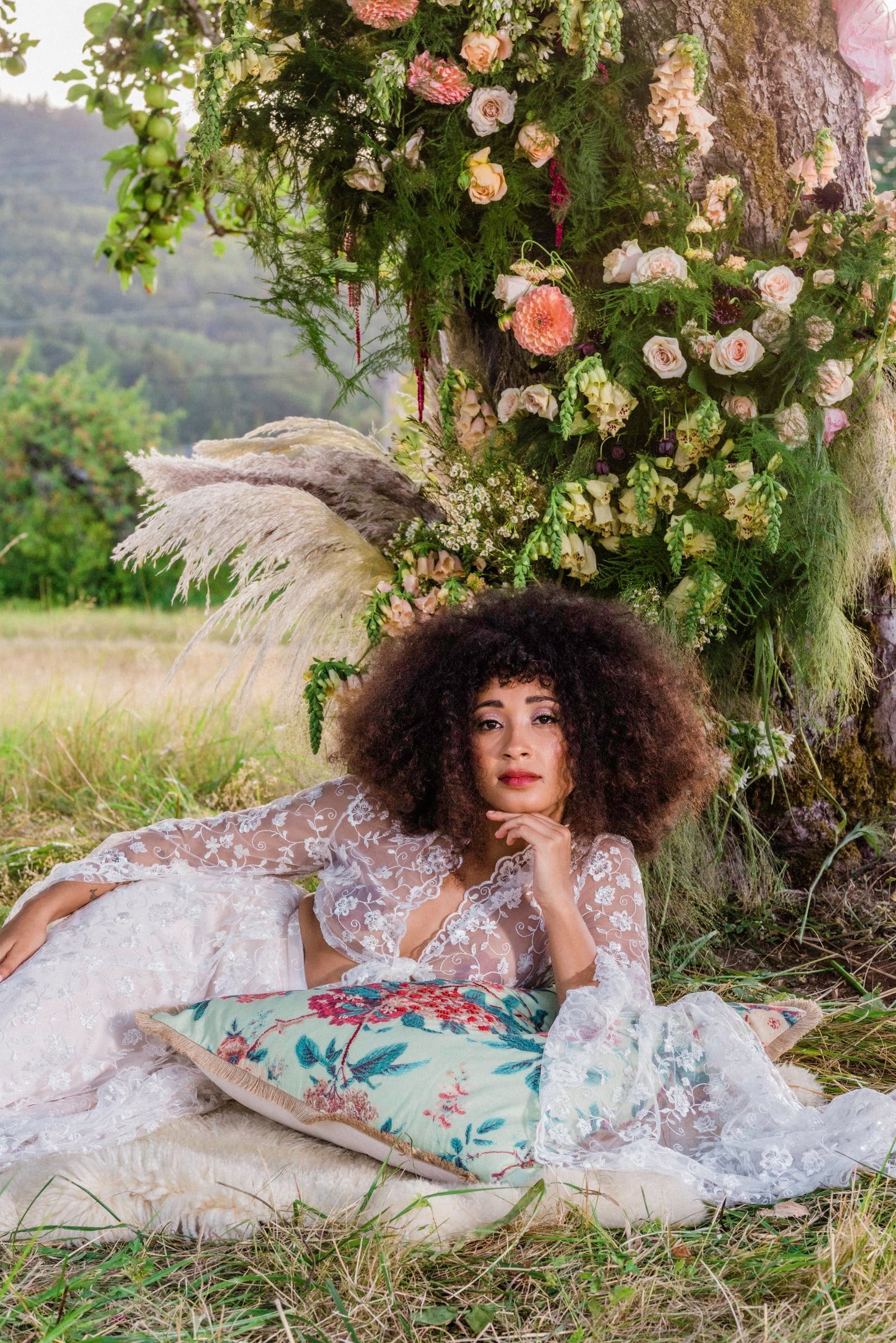 Woman with voluminous curls lounging in a flower garden