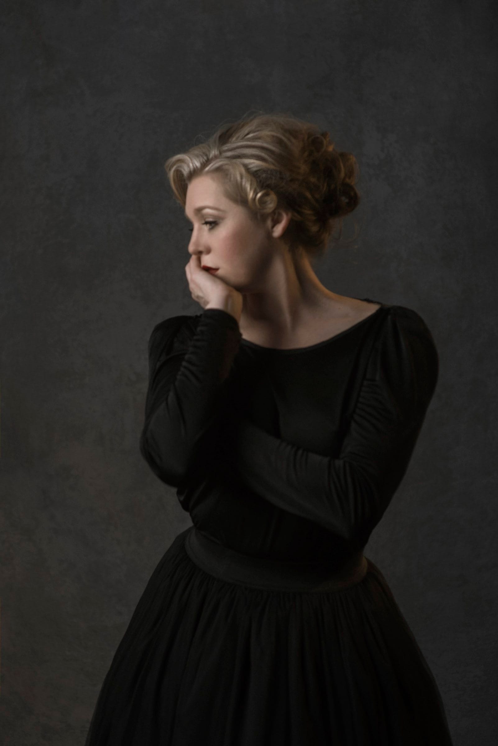 Fine art portrait of a woman in black against a dark backdrop