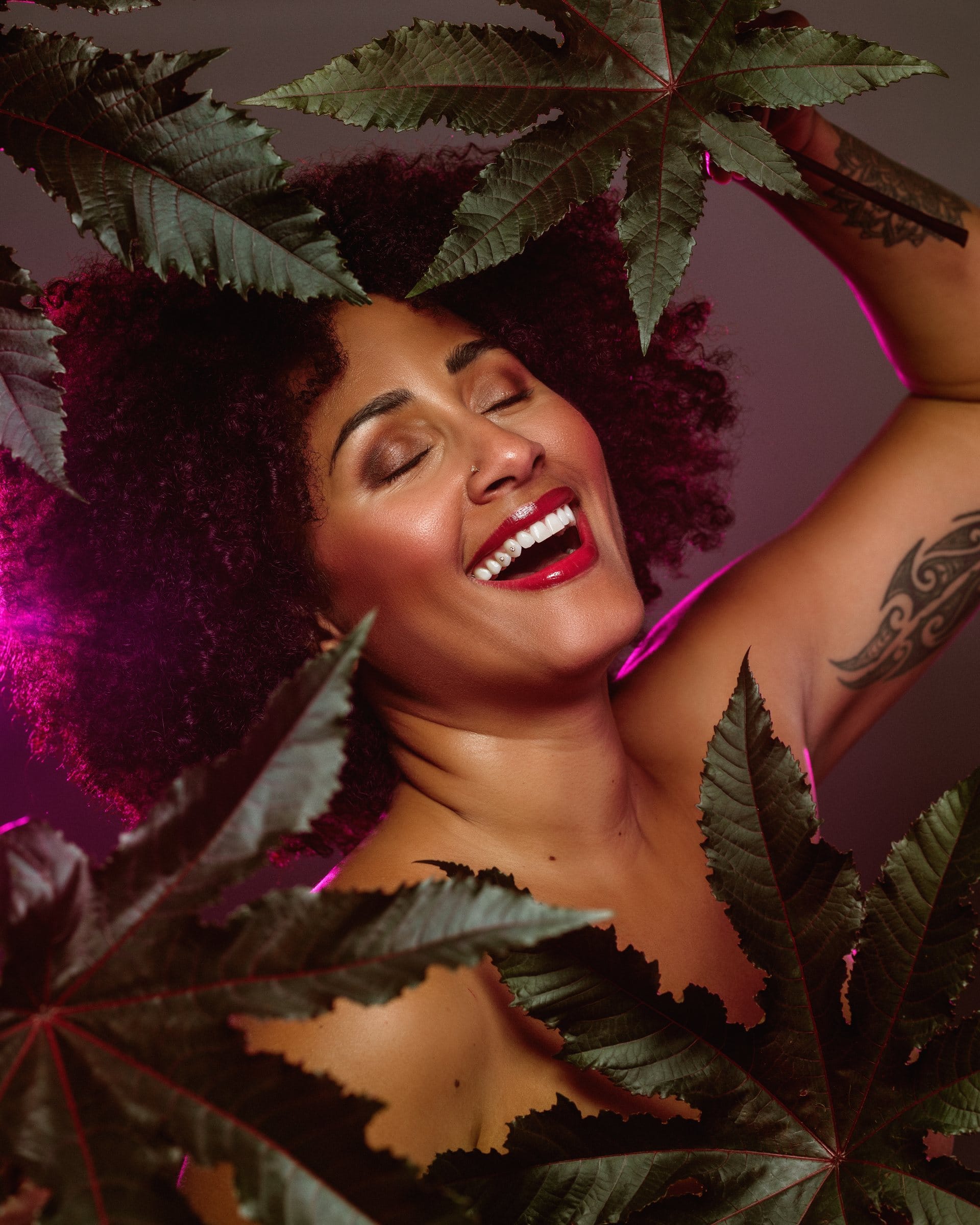 Joyful editorial portrait framed by leaves in magenta light