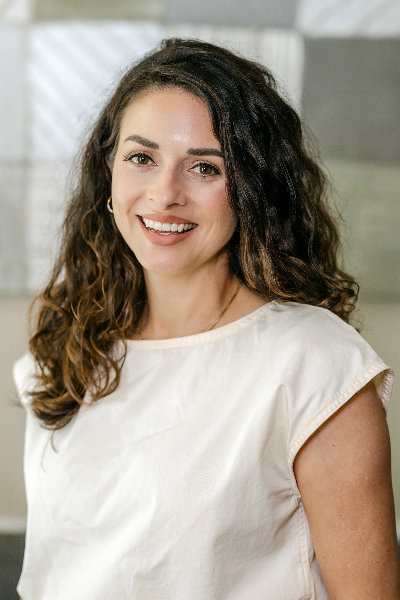 Curly-haired woman smiling in soft natural light