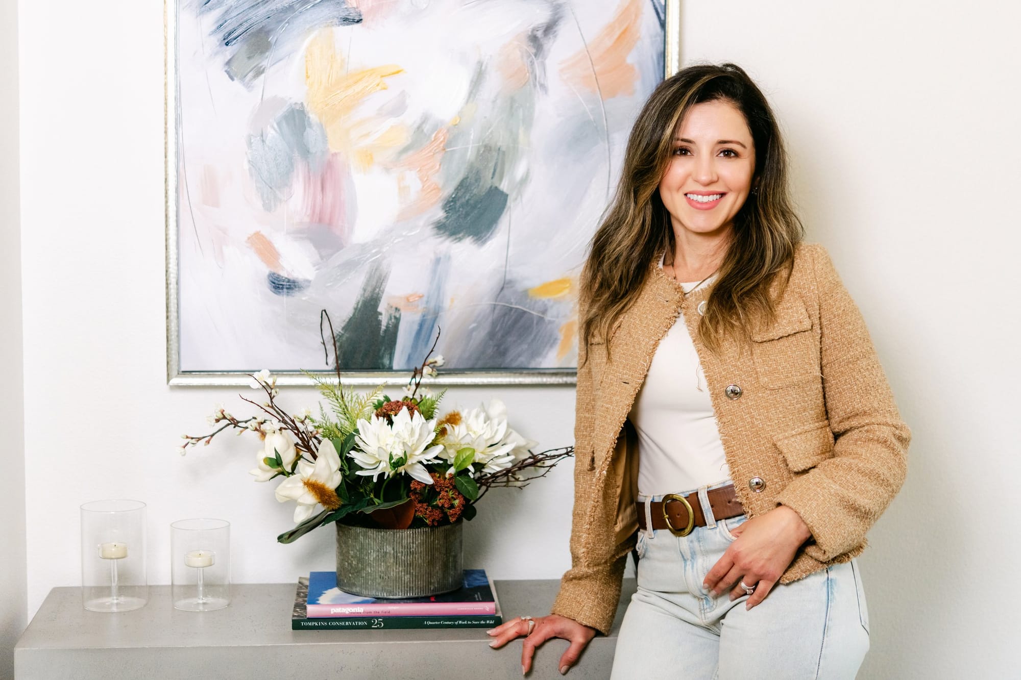 Woman in a camel jacket beside an abstract painting